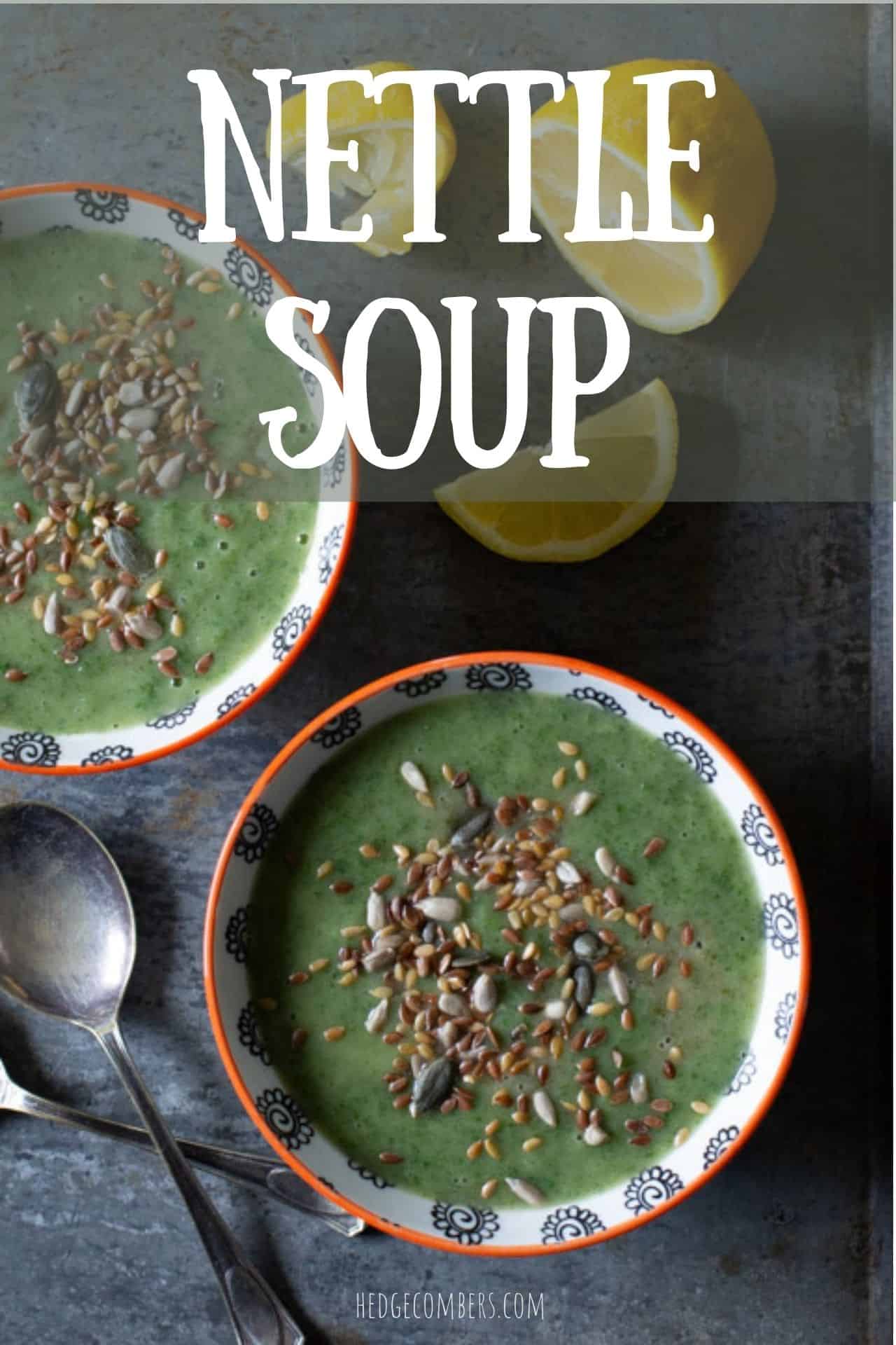 2 orange and white bowls filled with a green soup sprinkled with mixed seeds on a grey metal background with soup spoons and lemon slices