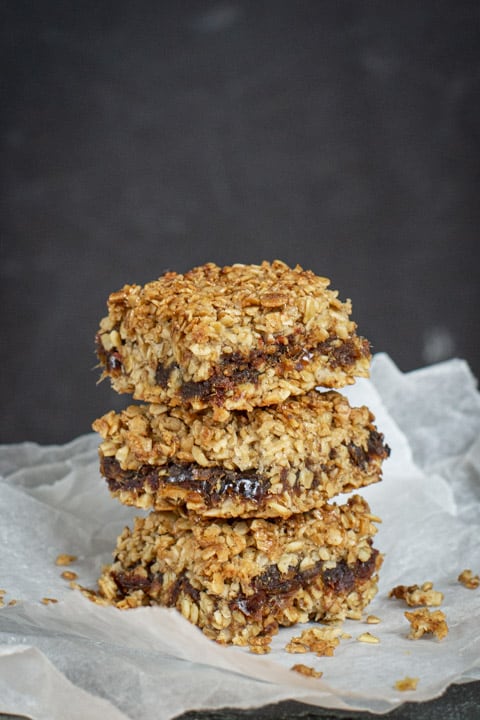 Three date flapjacks piled on top of each other on baking paper