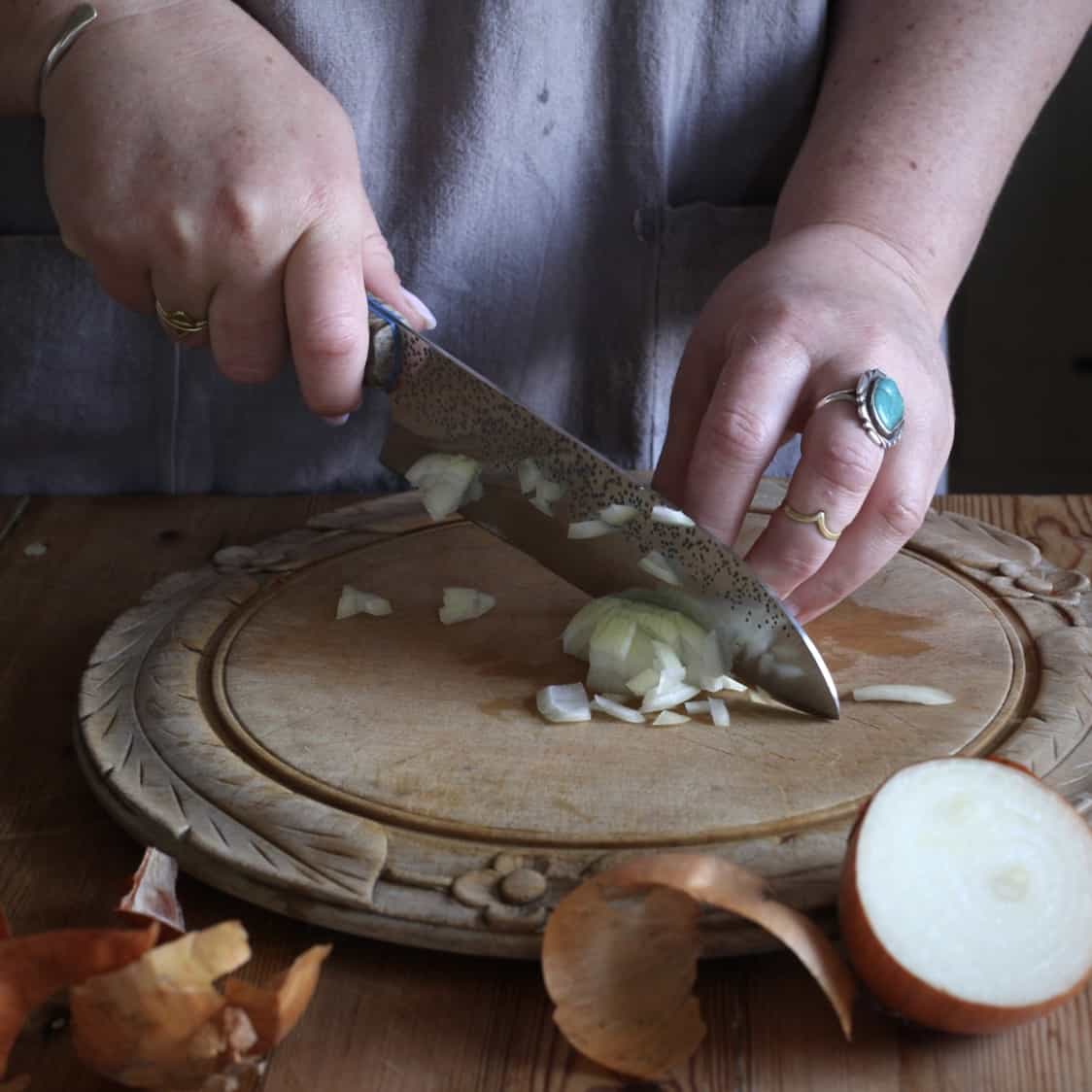 Womans hands chopping an onion of a Ogden chopping board