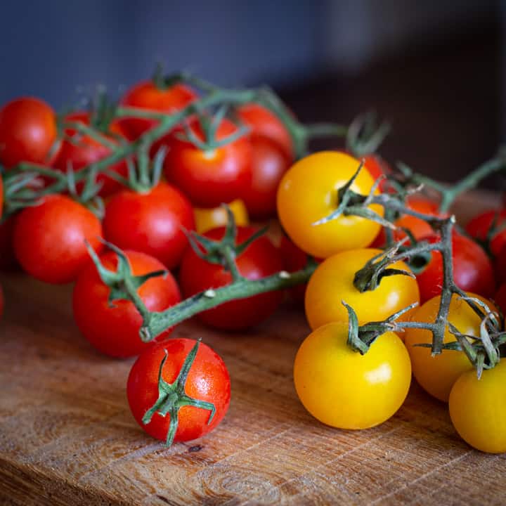 red and yellow cherry tomatoes on a wooden board