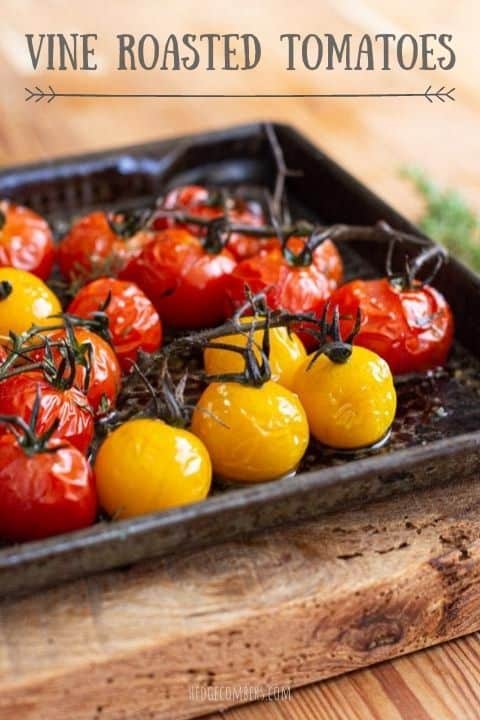 roasted red and yellow cherry tomatoes in a black baking tray on a wooden board