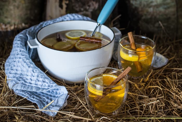 Two full glasses and a pan of hot Mulled scrumpy cider on straw bale 