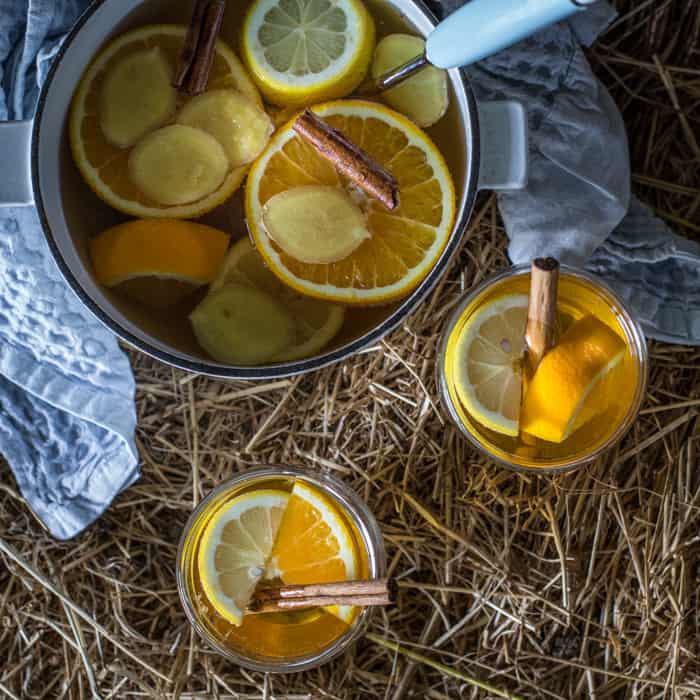 Two full glasses and a pan of hot Mulled scrumpy cider on straw bale 