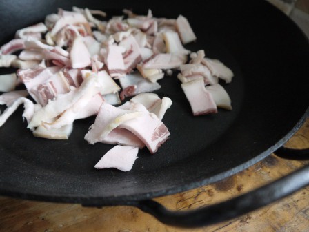 Rendering pieces of bacon fat in a cast iron skillet