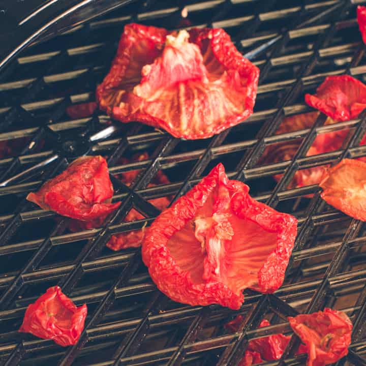 black dehydrator shelf with dried tomato halves on