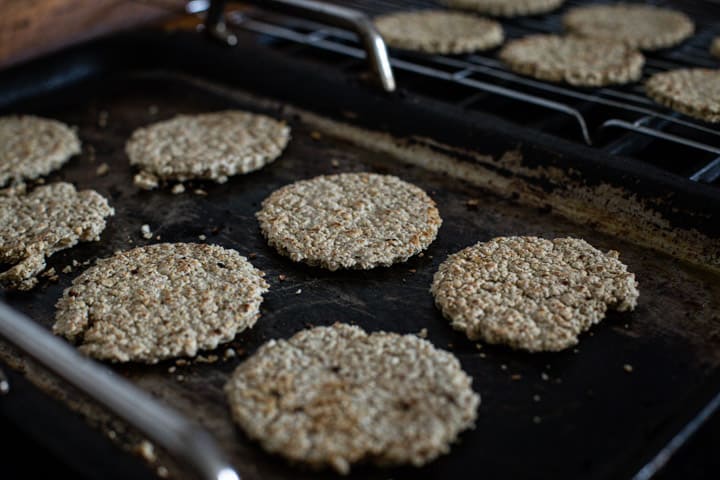 6 oatcakes cooking on a black stove griddle 