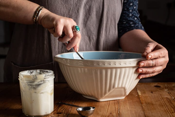 womans hands mixing in a blue and white bowl with a metal spoon