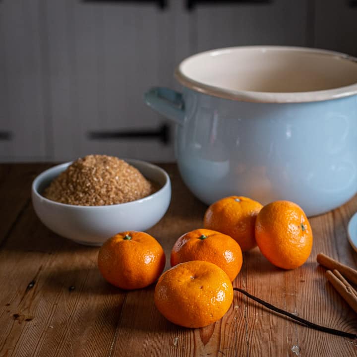 rustic kitchen country with a pale blue enamel pan, satsumas, brown sugar in a pale blue bowl and cinnamon sticks