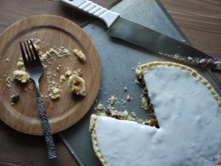 Christmas Mince Pie with icing on it, piece cut out and a wooden plate with a fork and crumbs on it