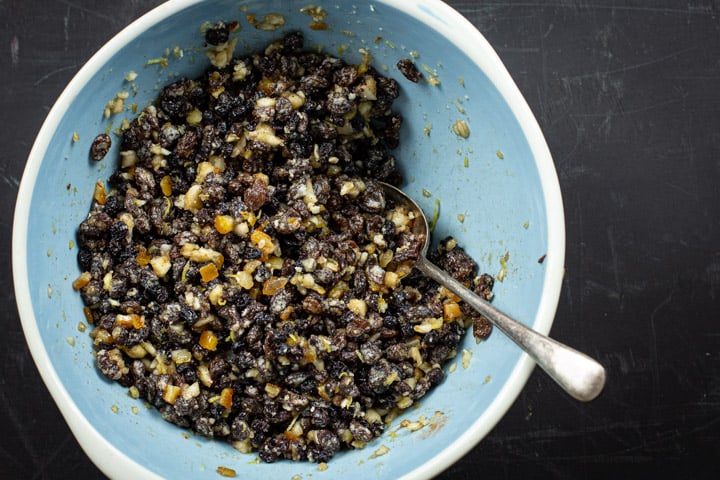 Blue bowl full of mincemeat mixture with a spoon in it