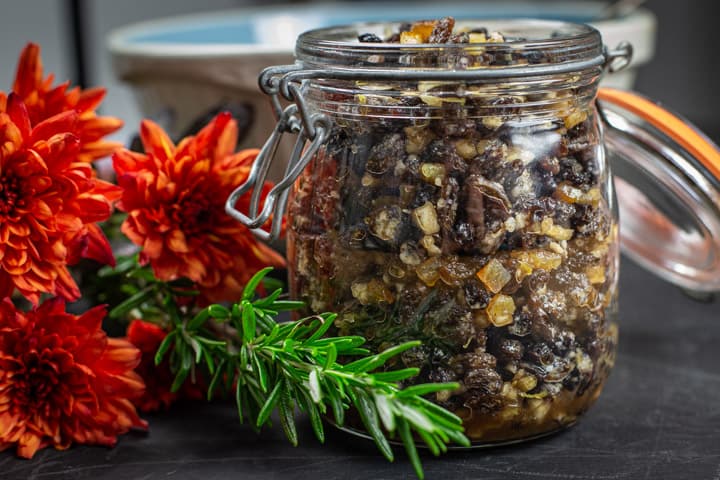 Open jar of best mincemeat recipe next to orange flowers and leaves