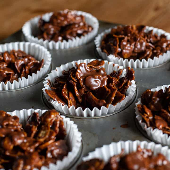 chocolate covered cornflake cakes in white paper cases in a metal baking tray