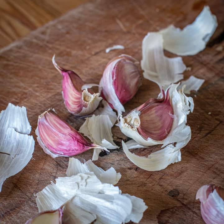 pretty pink garlic cloves on a wooden chopping board