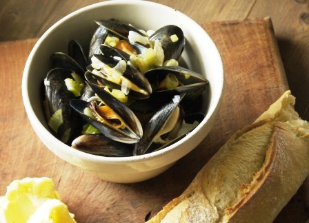 Dairy Free Moules Mariniere in a white bowl with french bread on a wooden board