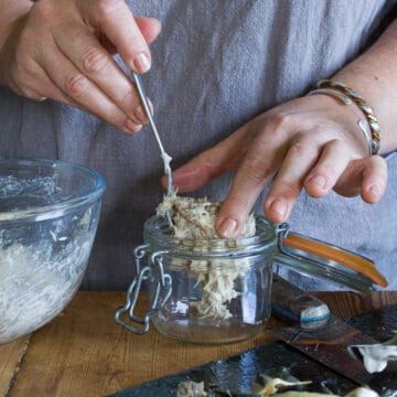 Woman spooning freshly made smoked mackerel pate into a small glass killer jar