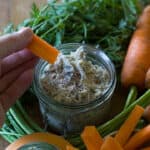 Woman’s hand holding a carrot crudité with a mound of smoked mackerel pate on the end