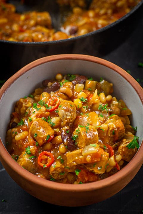 Bowl of cowboy stew with a pan of the stew in the background