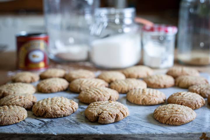 messy kitchen with baking supplies and a fresh batch of ginger biscuits on the wooden counter