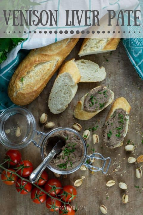 wooden backgrouns with messy supper spread showing sliced baguette, cherry tomatoes, pistachios and a glass jar of homemade pate sprinkled with parsley