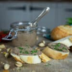 rustic kitchen backdrop with small glass jar of fresh homemade pate, slices of bread and fresh green parsley
