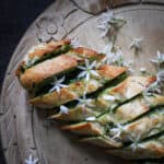 Freshly baked golden garlic bread scattered with retry white wild garlic flowers