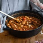 woman holding a small Dutch oven of cowboy sausage stew