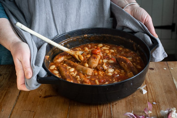 woman holding a small Dutch oven of cowboy sausage stew