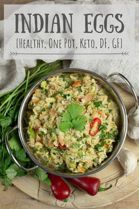 metal bowl of Indian Eggs against a wooden background with fresh coriander and red chillis