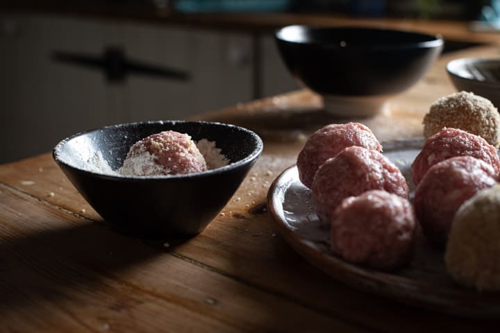 messy kitchen scene with a tray of scotch eggs ready to be deep fried