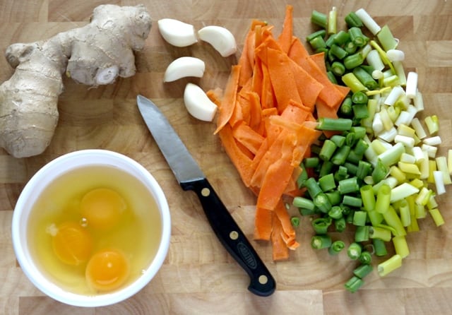 ingredients for Healthy Egg Fried Rice on a chopping board with a knife