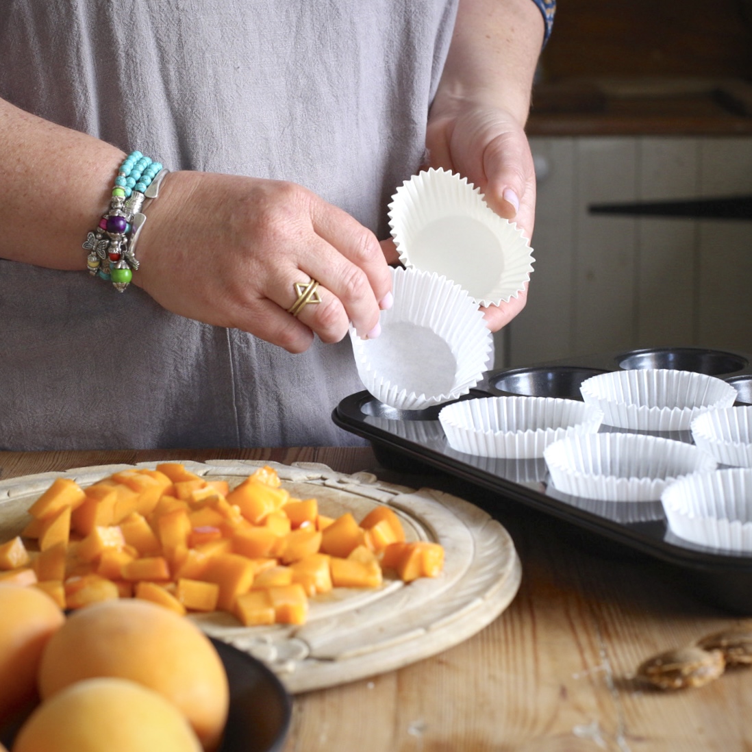 Woman placing white paper muffin cases into a black muffin tin