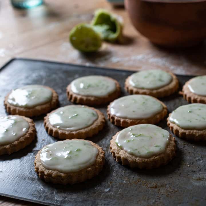 dark grey baking sheet topped with several iced ginger cookies on a wooden counter