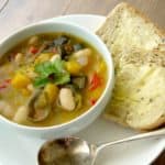 Deep bowl of veggie pumpkin and butterbean stew served with bread and butter
