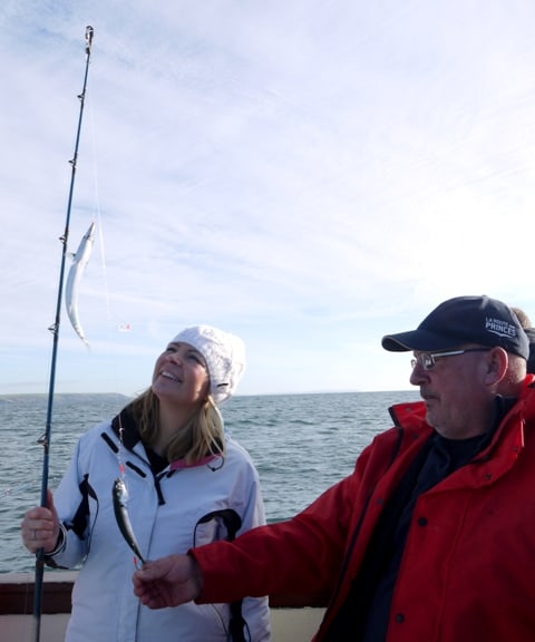 Jennie holding a fishing line with 2 mackerel