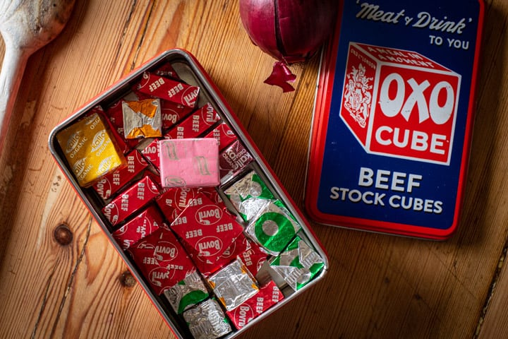 wooden kitchen counter with red OXO tin filled with various flavoured stock cubes