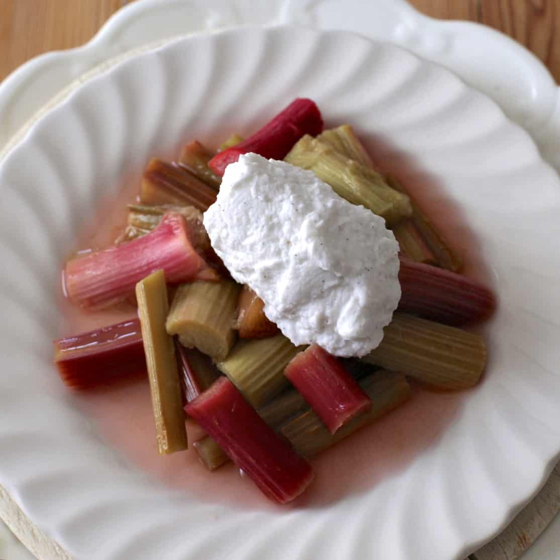 Overhead shot of a white plate topped with poached rhubarb and whipped coconut cream