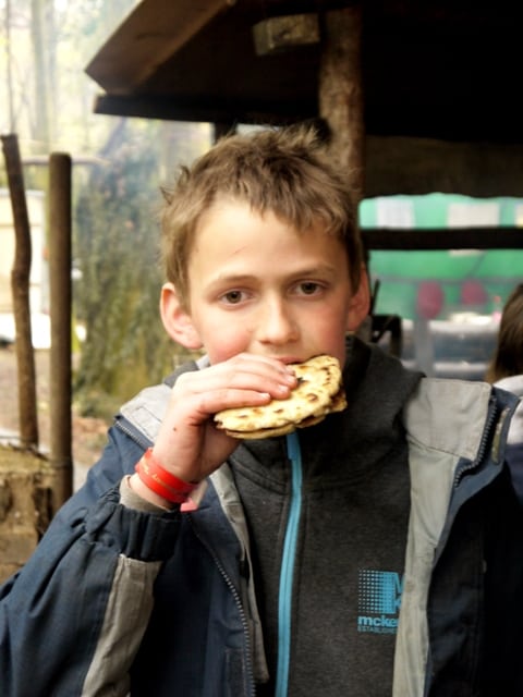 boy eating Flatbread cooked on campfire