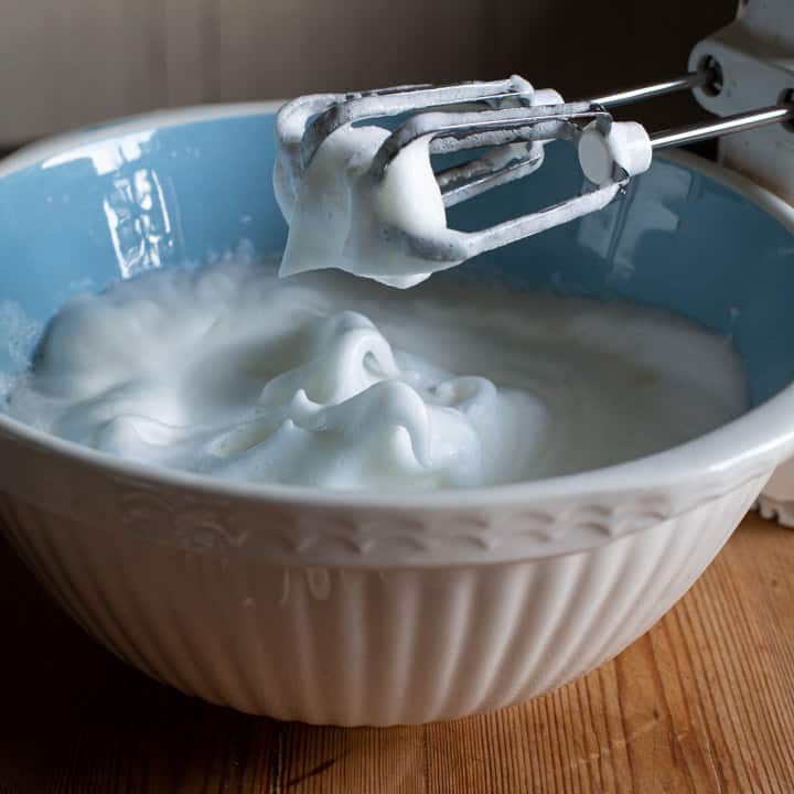 blue and white mixing bowl full of frothy egg whites 