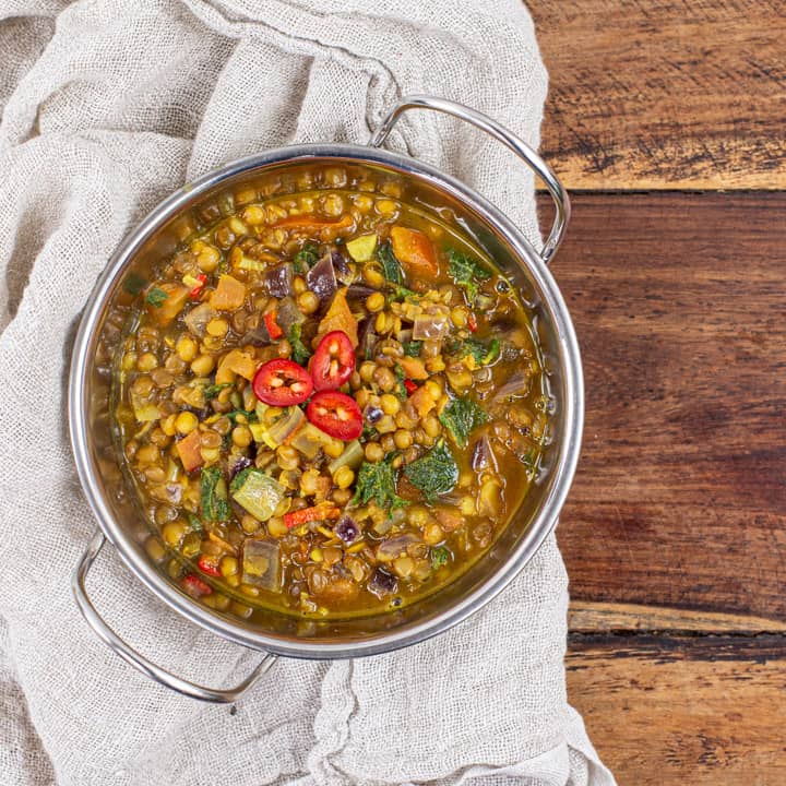 metal bowl of lentil curry on a wooden background