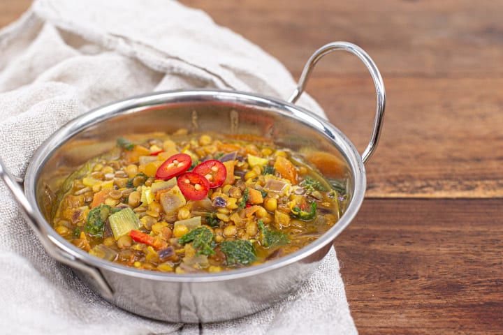 metal bowl of lentil curry on a wooden background