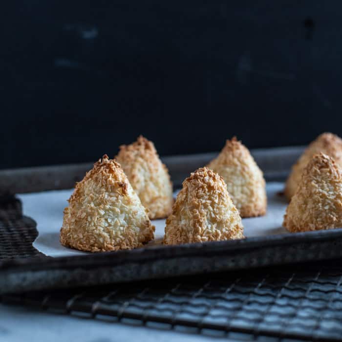 little golden coconut pyramid cakes on a baking sheet lined with baking paper