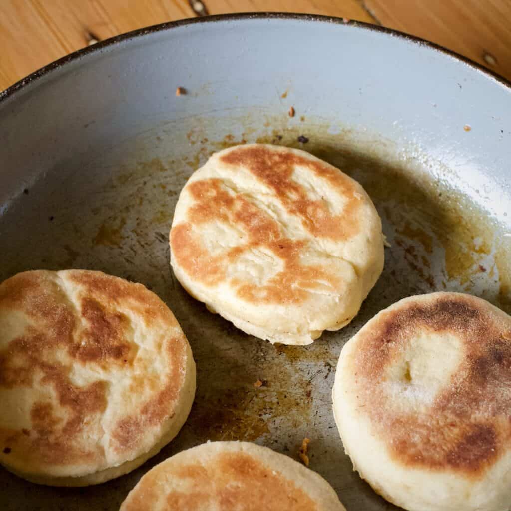 4 griddle cakes cooking on a grey frying pan