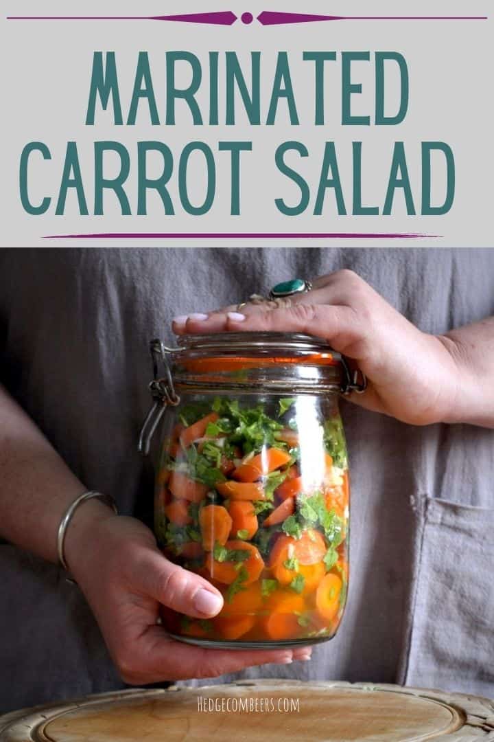 Woman’s hands holding a large glass jar filled with chopped carrots, green coriander and pieces of garlic