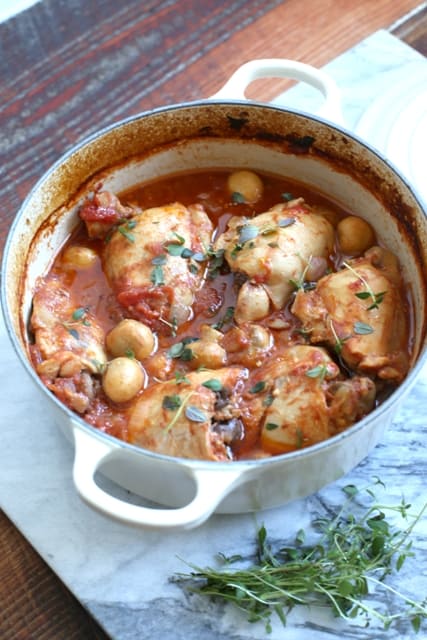 Simple Country Chicken Casserole in a white casserole dish with a sprig of thyme