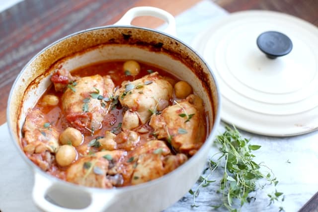 Simple Country Chicken Casserole in a white casserole dish with a sprig of thyme