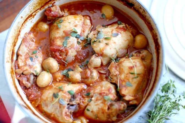 Simple Country Chicken Casserole in a white casserole dish with a sprig of thyme