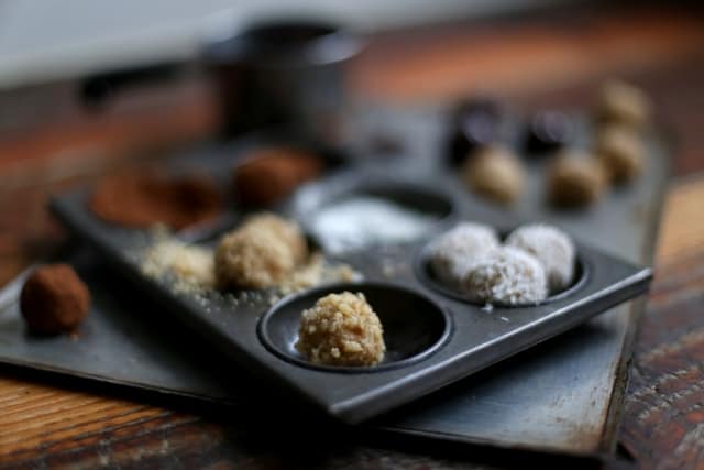 messy baking shot with handmade cookie dough truffles on a metal baking sheet with melted dark chocolate 