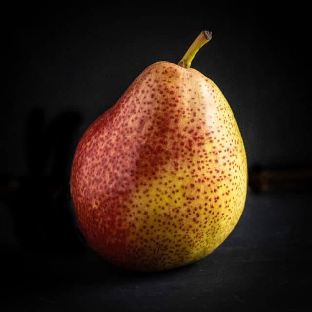 A perfect, ripe pear on a black background