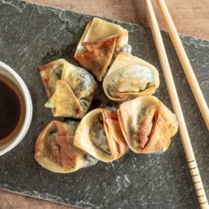 6 crispy cooked vegetarian wontons served on a slate with chopsticks