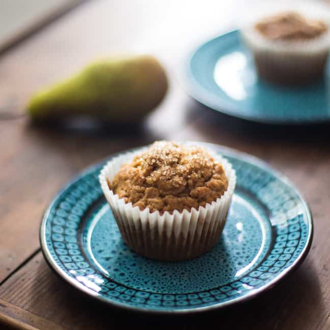 Pear and Pistachio Muffins on blue plates sitting on a wooden tray with a fresh pear